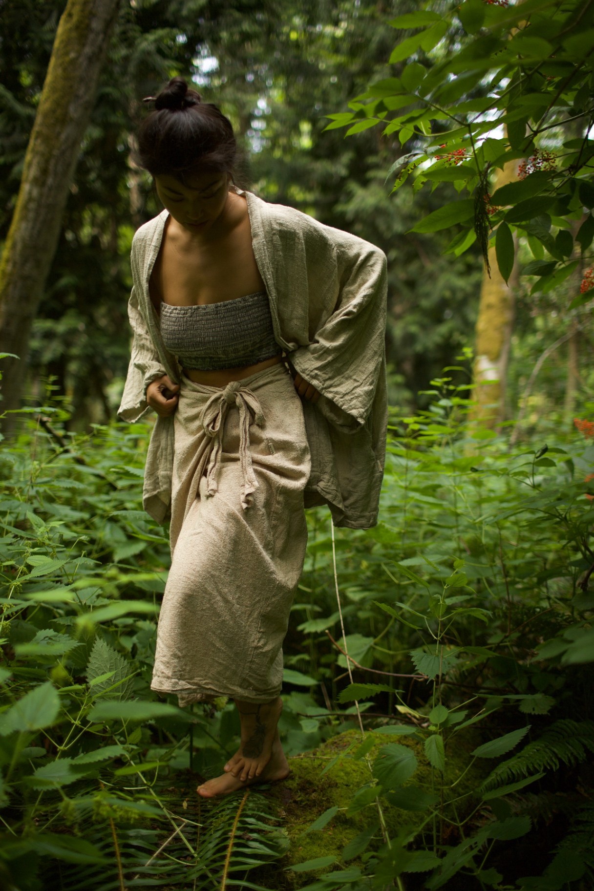 Person wearing natural linen garments walking through a green forest