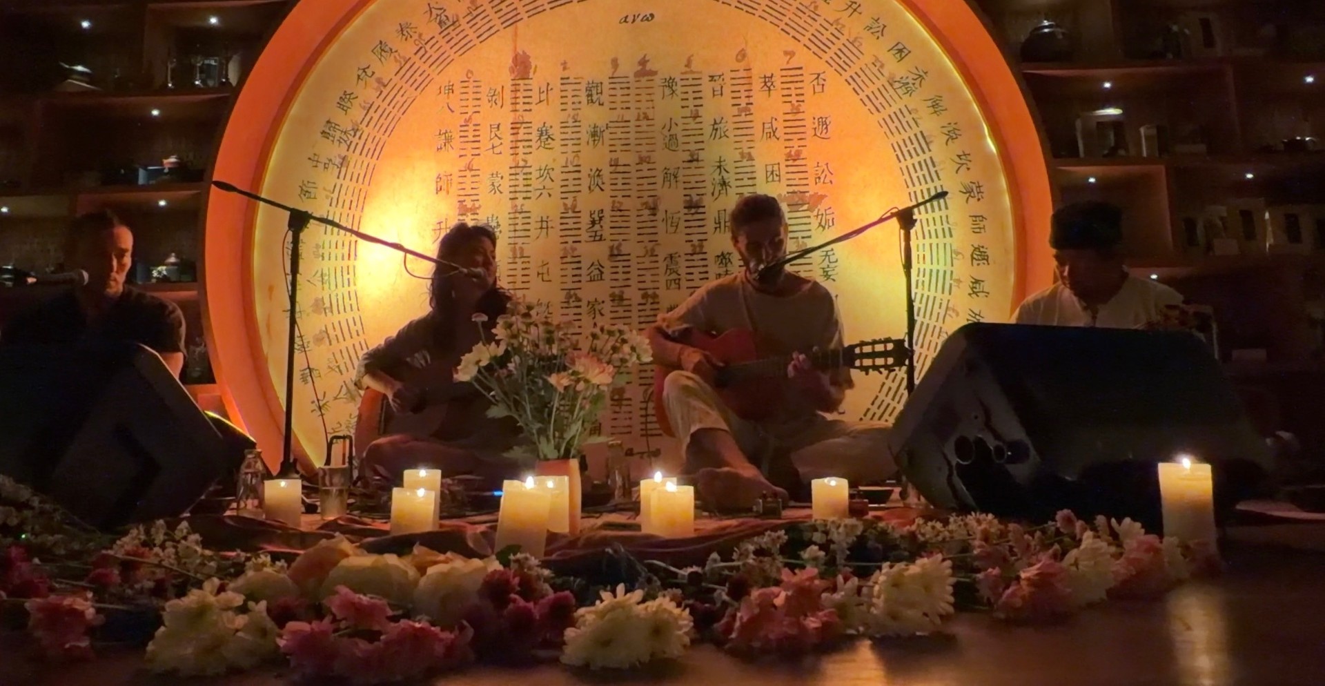 Intimate candlelit concert with guitars, flowers, and a glowing I Ching mandala